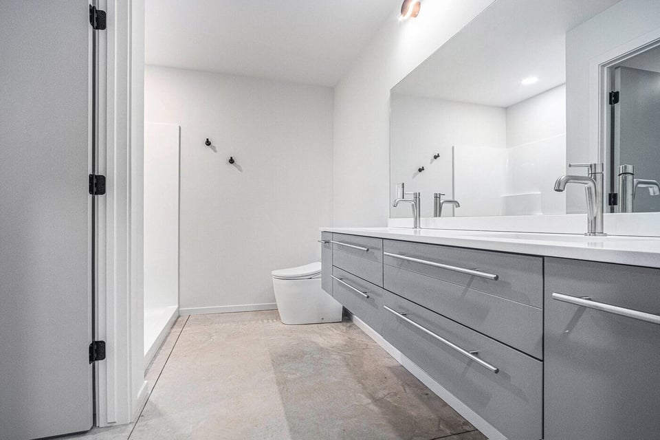 Modern West Michigan bathroom with gray double vanity, white countertop and polished concrete floor
