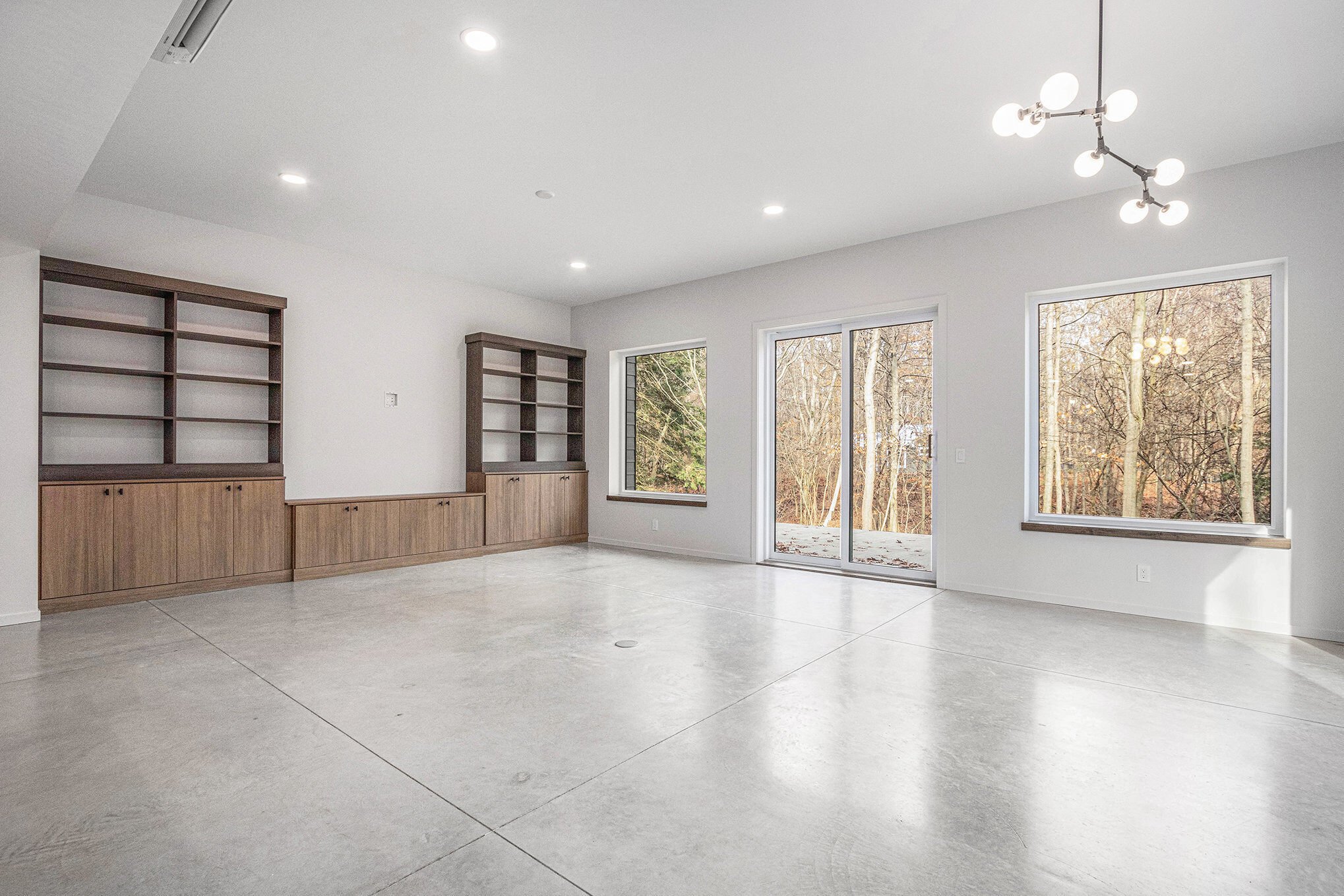 Michigan Custom Home South Haven with built in wood cabinets and open shelves, polished contrete floor, large windows, and exterior view. 