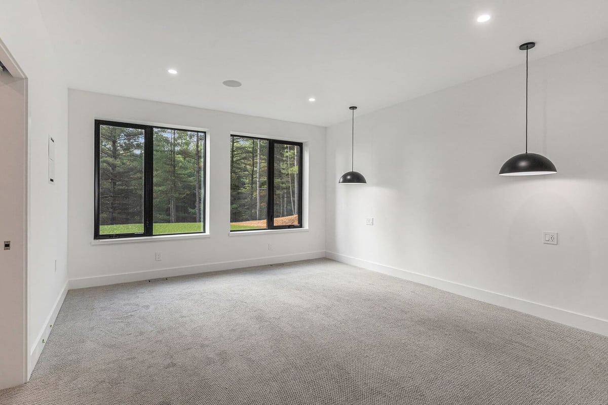 Bright bedroom with large windows and black pendant lighting in West Michigan by R-Value Homes