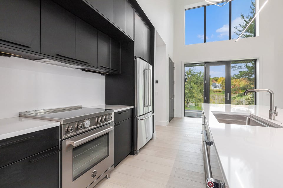 Bright modern kitchen in West Michigan with black cabinets and large windows, remodeled by R-Value