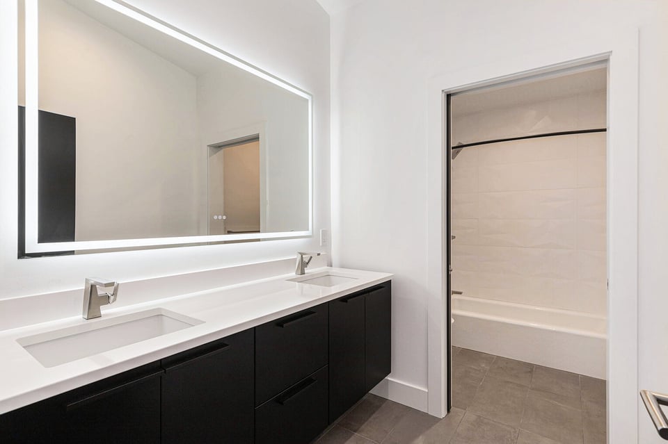 Modern bathroom in West Michigan home built by R-Value Homes featuring double sinks and a tub-shower combo