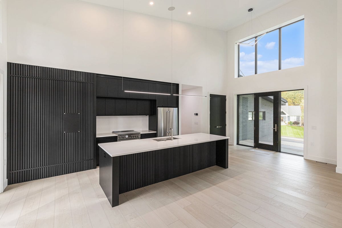 Modern black and white kitchen with tall ceilings and large windows in West Michigan