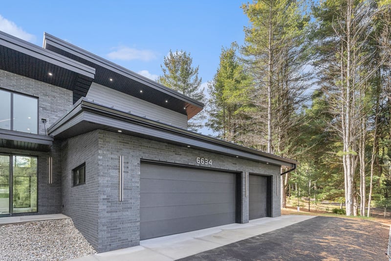 Modern home exterior with dark gray brick and flat roof in West Michigan, featuring a three-car garage