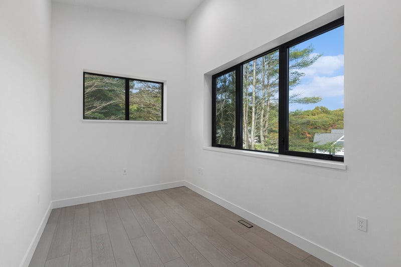 Sunlit West Michigan office or bedroom with wide-plank flooring and large black-framed windows, by R-Value Homes