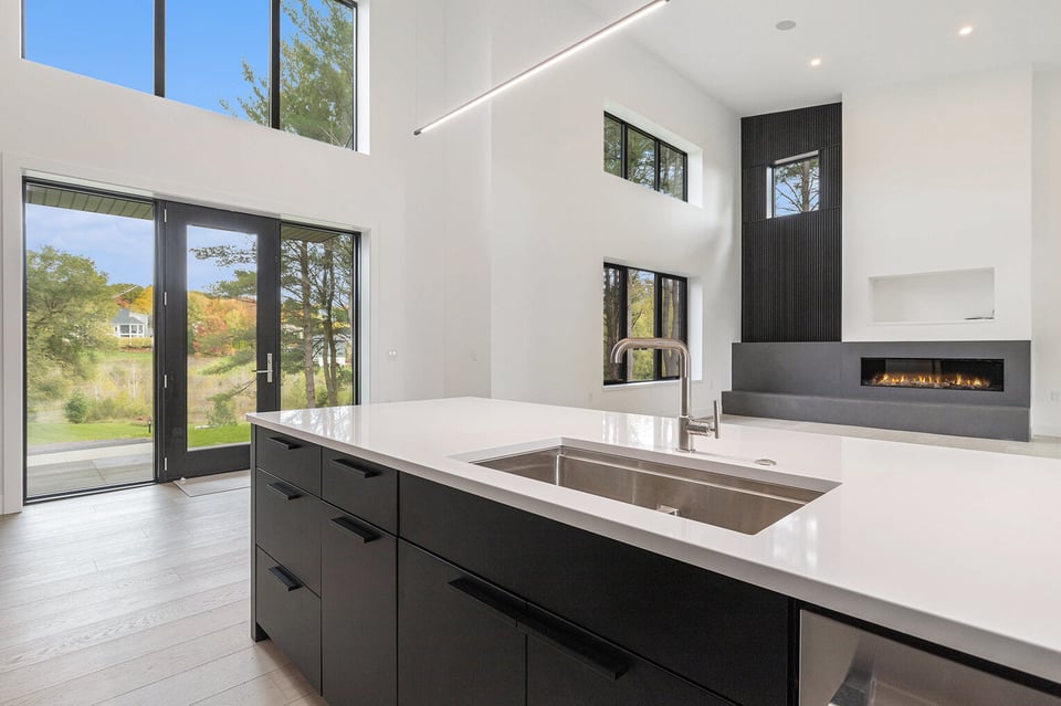 West Michigan kitchen with black cabinets and sliding patio doors to a wooded backyard