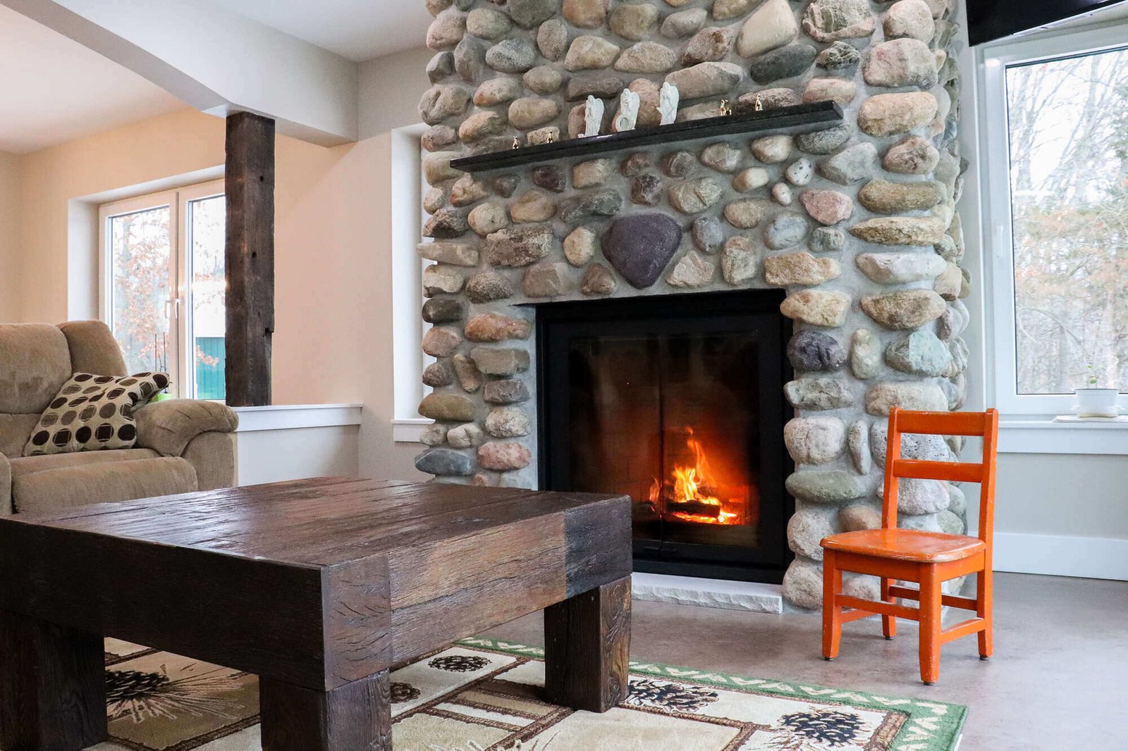 Cozy custom living room with a stone fireplace and rustic decor in a custom home by R Value Homes in West Michigan