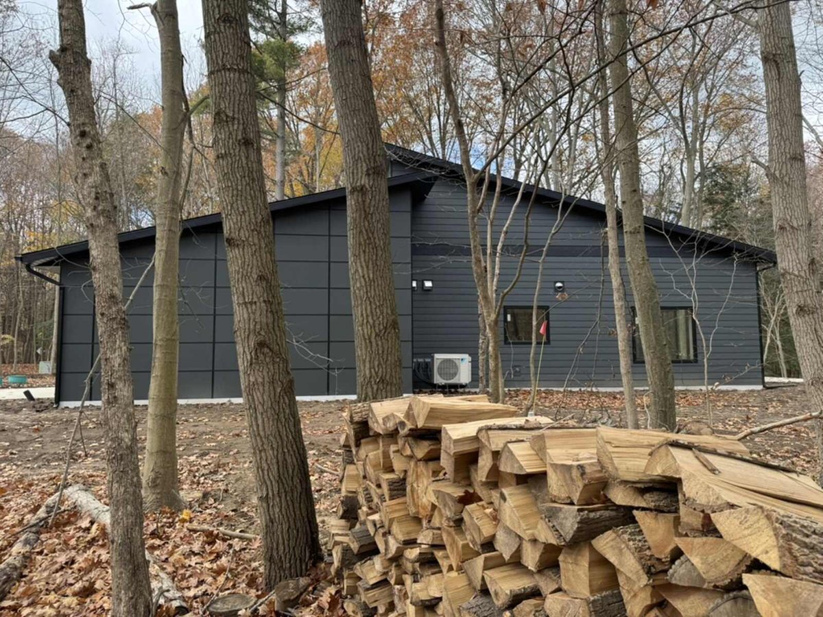 Side exterior view of a custom-built modern home by R Value Homes in West Michigan, surrounded by trees