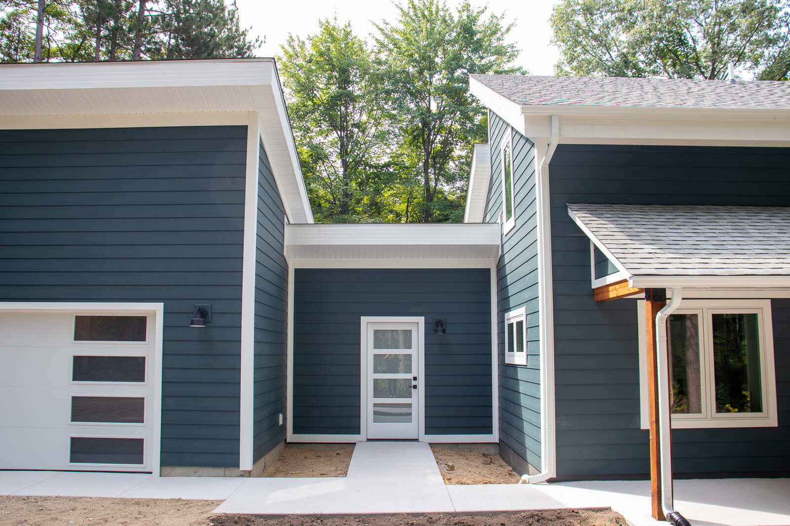 Garage entry of a custom-built West Michigan home by R-Value Homes, with sleek white doors and dark siding Garage entry of a custom-built West Michigan home by R-Value Homes, with sleek white doors and dark siding