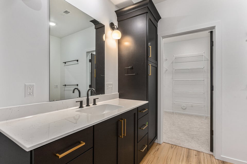 Custom bathroom vanity with black cabinets and gold accents by R-Value Homes in West Michigan
