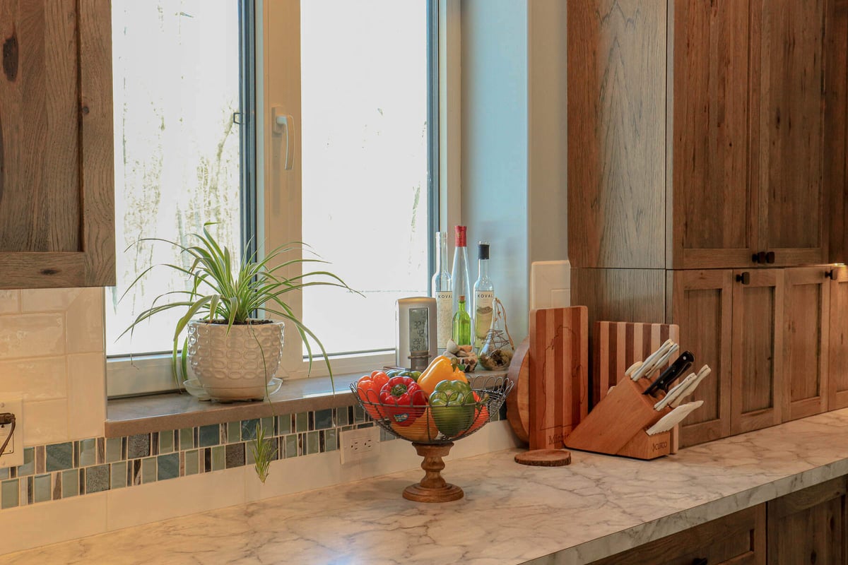 Bright kitchen countertop with fresh produce and wooden cabinets by R-Value Homes, West Michigan