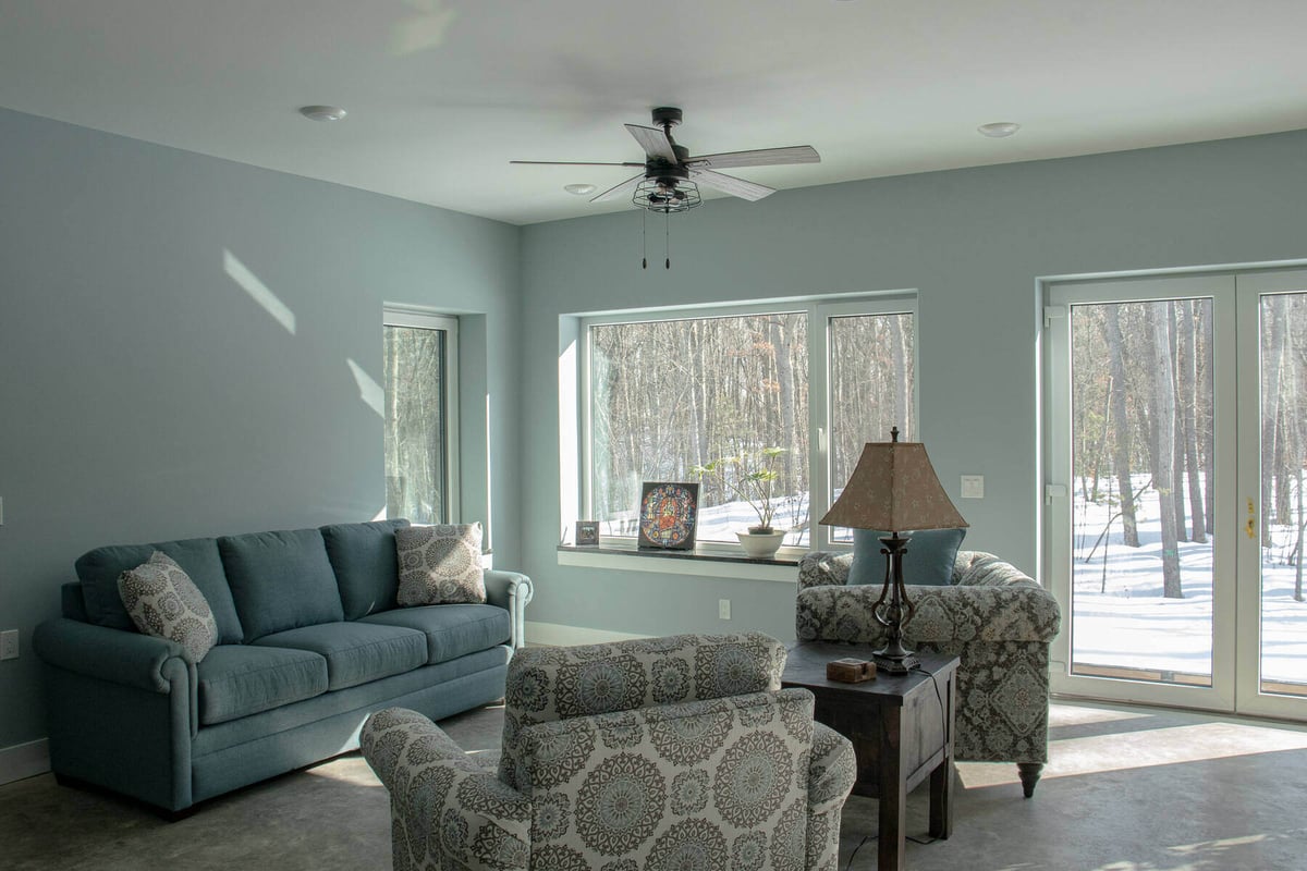 Bright living room with large windows and modern furniture in a custom West Michigan home by R-Value Homes