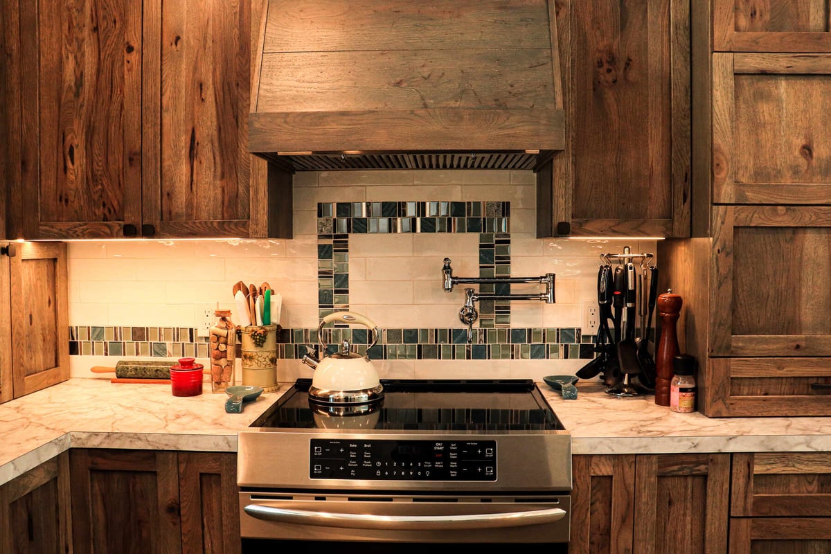 Detailed backsplash with mosaic tiles and wood cabinetry in a custom kitchen by R-Value Homes, West Michigan