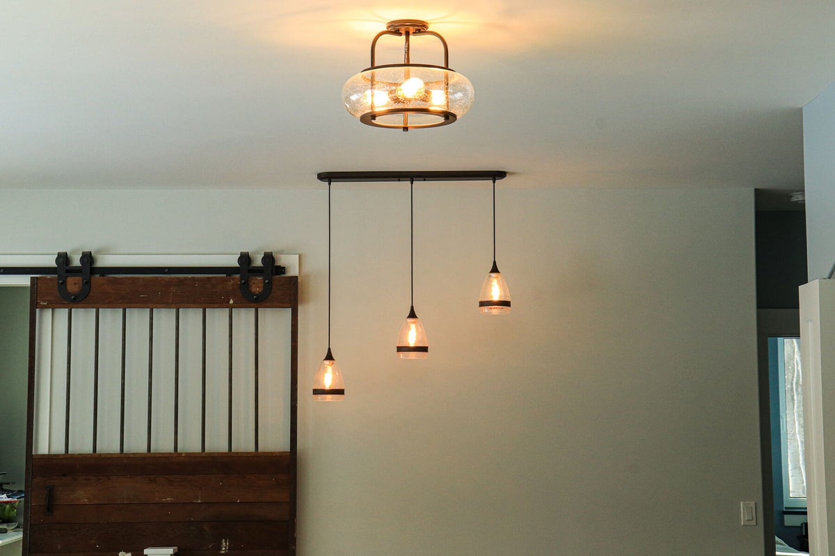 Rustic barn-style sliding door and industrial pendant lights in a custom home by R-Value Homes in West Michigan