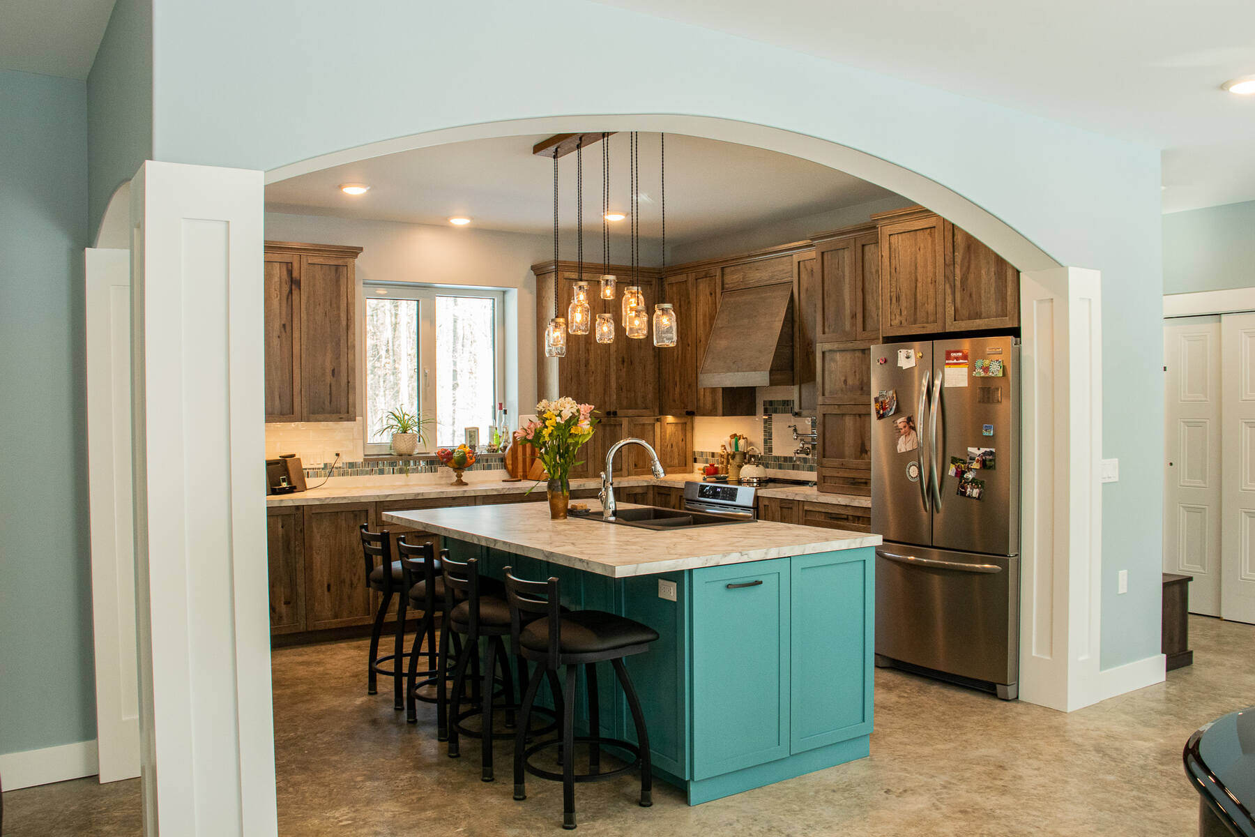 Rustic kitchen with wood cabinetry and a teal kitchen island by R-Value Homes in West Michigan