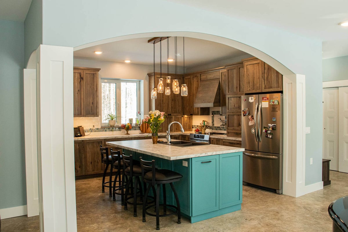 Rustic kitchen with wood cabinetry and a teal kitchen island by R-Value Homes in West Michigan