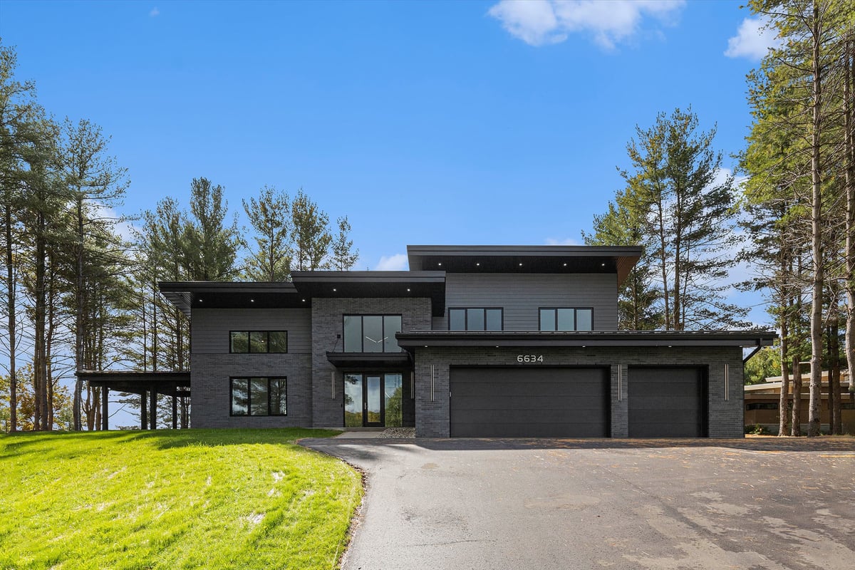 Full exterior view of a custom-built home by R-Value Homes in West Michigan with a modern black roof and black siding and sunroom
