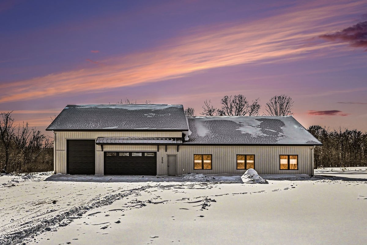 Full exterior view of a custom-built ranch-style home in West Michigan with a modern black roof and cream siding