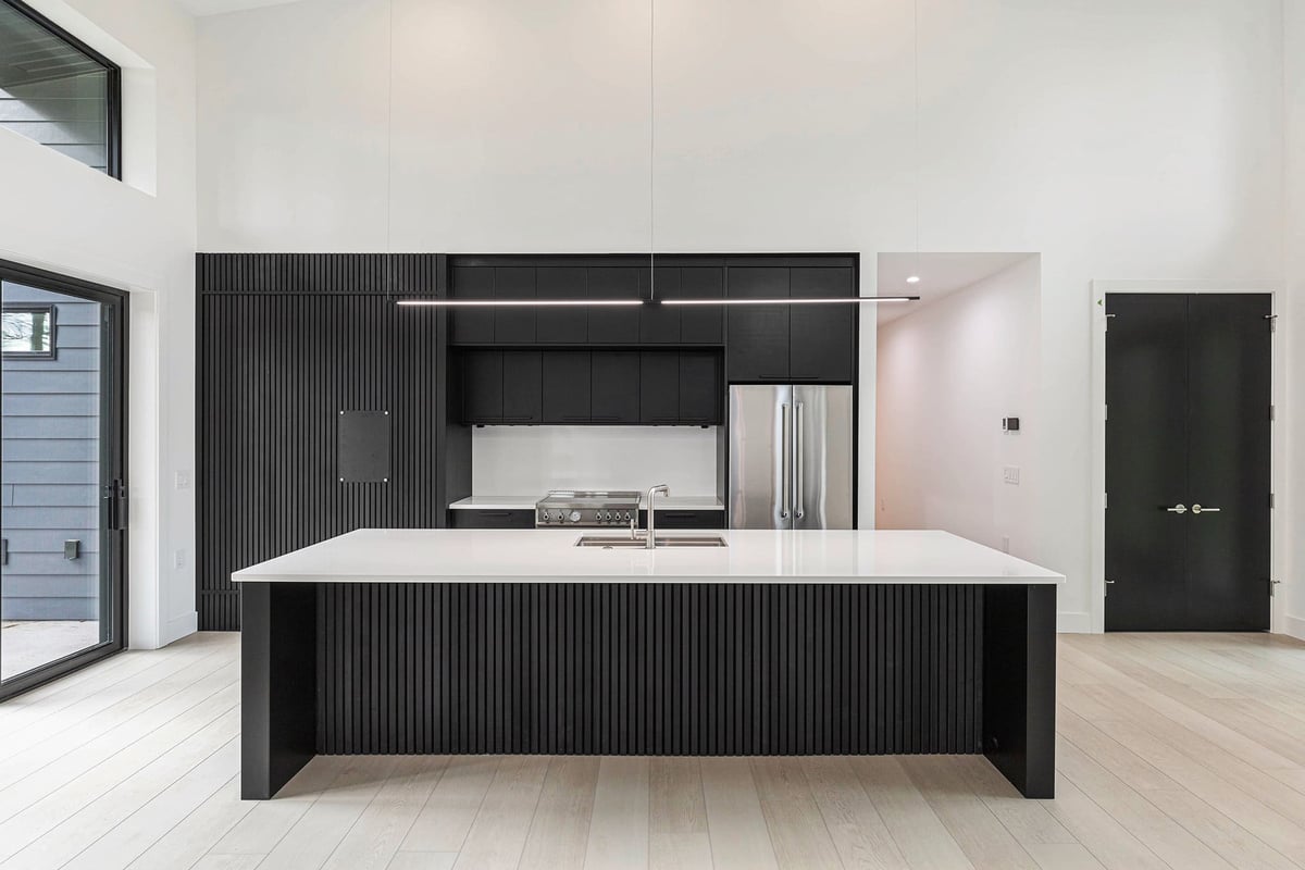 Large modern kitchen with black island and black cabinetry in a custom-built West Michigan home by R-Value Homes