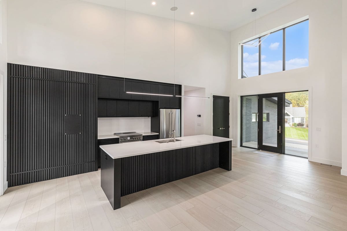 Large modern open-concept kitchen with black cabinetry in a custom-built West Michigan home by R-Value Homes