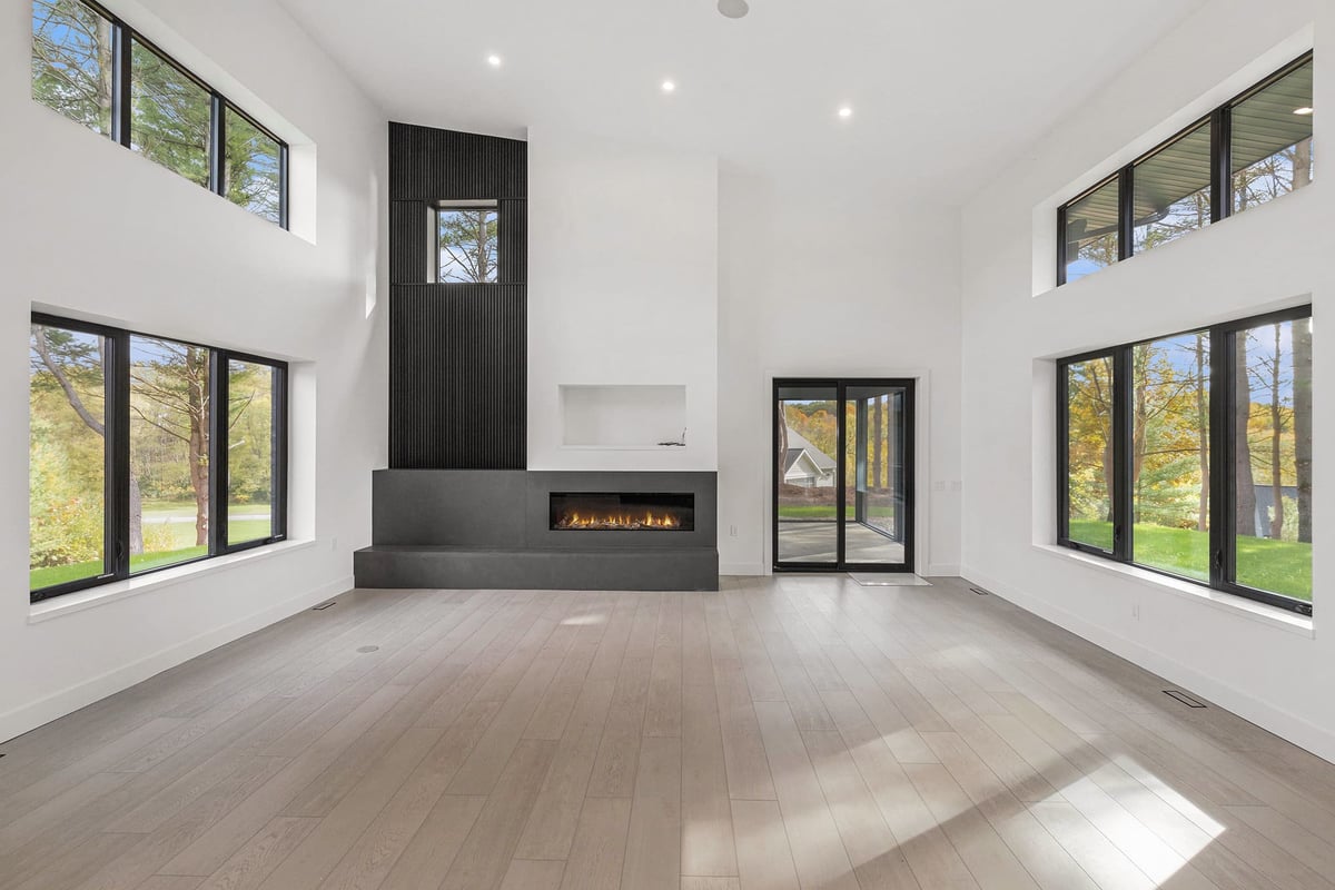 Large open concept living room with high ceilings, large windows and fireplace in a custom home built by R-Value Homes in West Michigan
