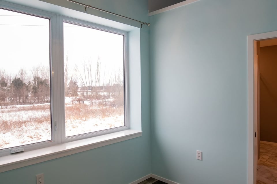 Light blue room with large window, snowy outdoor view, and doorway, located in West Michigan