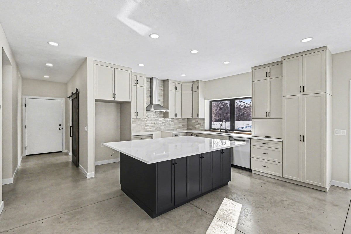 Modern kitchen with dark island and white cabinetry in a custom-built West Michigan home