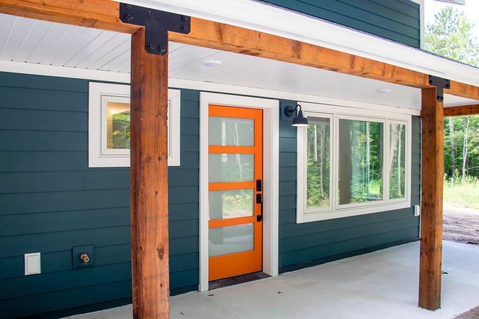 Orange front door on a blue custom home built by R-Value.