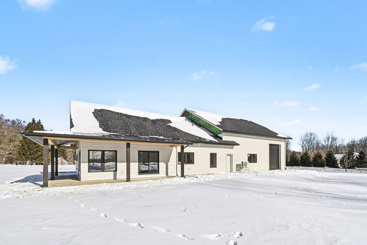 Rear view of a custom-built West Michigan home by R-Value Homes, showcasing a spacious backyard and wrap around covered porch
