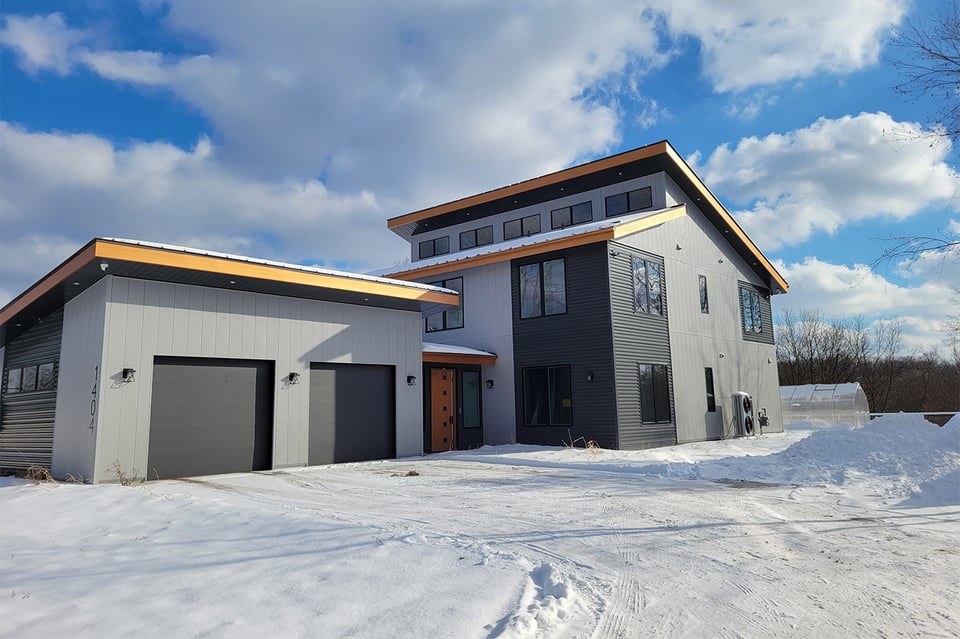 Modern black and gray home in snowy West Michigan with flat rooflines and tall windows