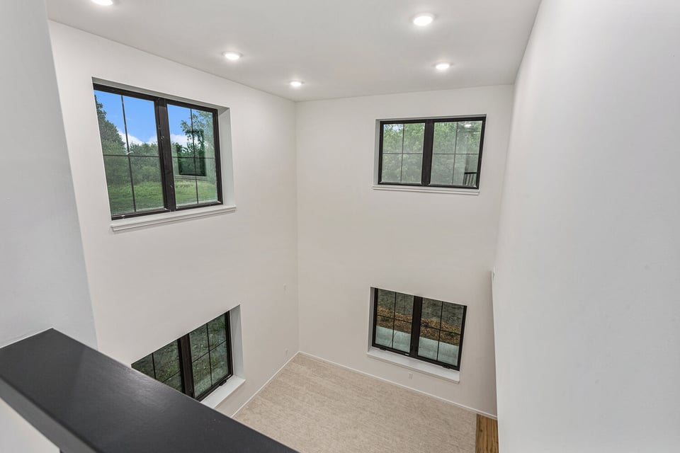 Bright two-story living space in West Michigan with tall windows and clean white walls, designed by R-Value Homes