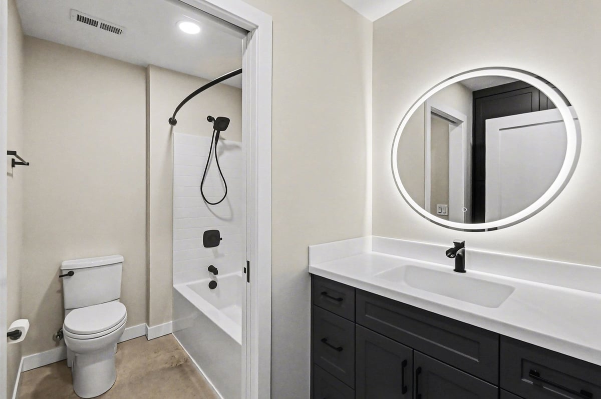 secondary bathroom with modern mirror and black accents in a custom home in west michigan