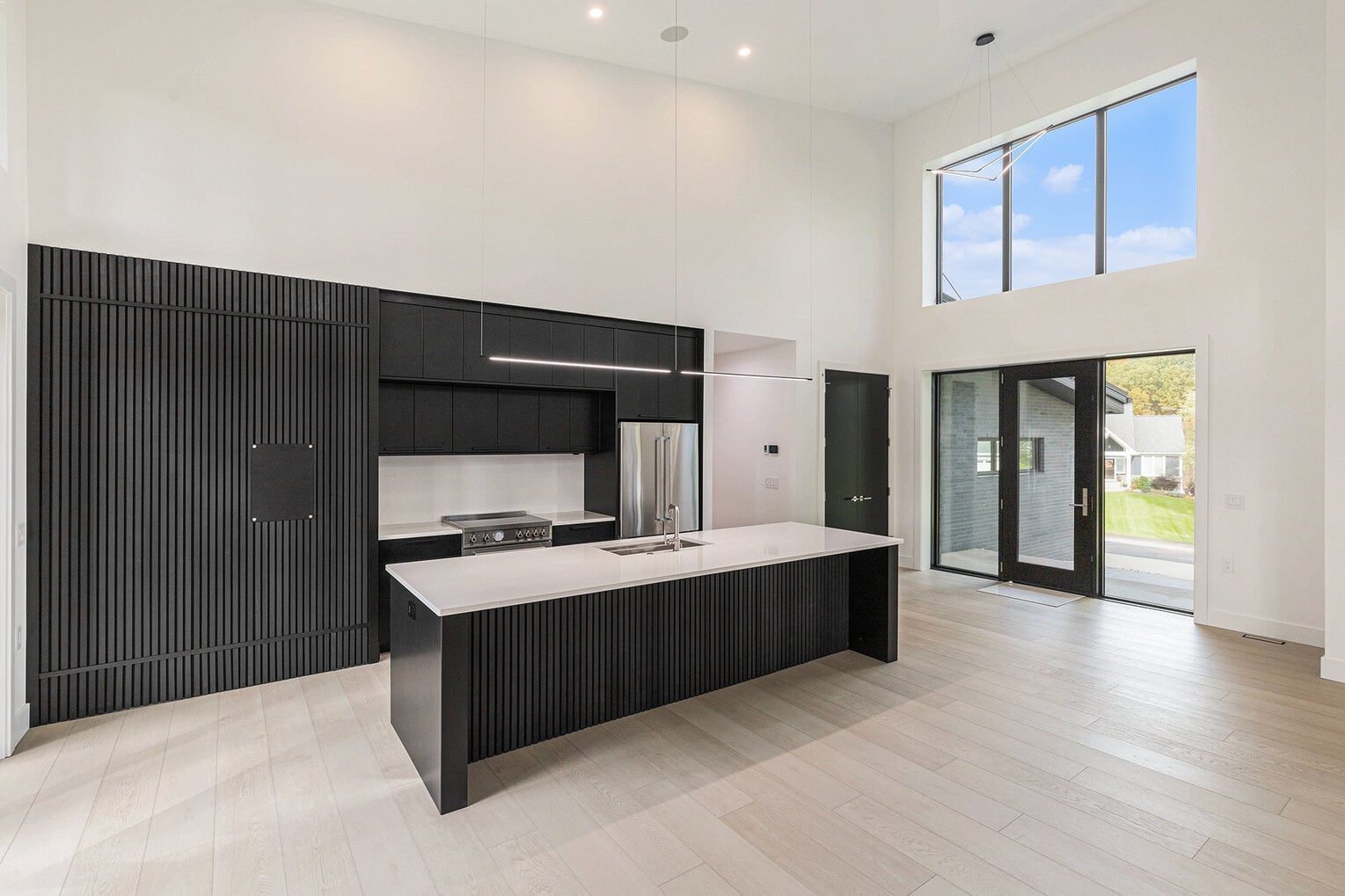 Modern black and white kitchen with tall ceilings and large windows in West Michigan